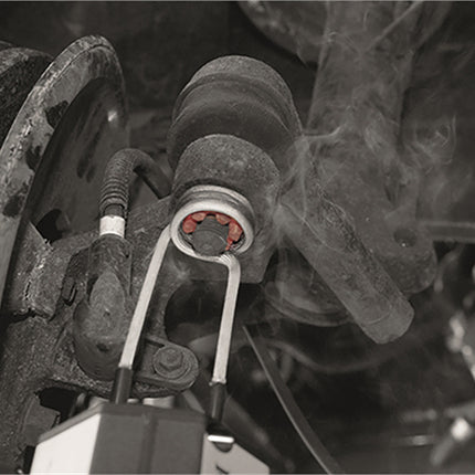 Venom induction heater with coil attached, heating a seized part on a vehicle.